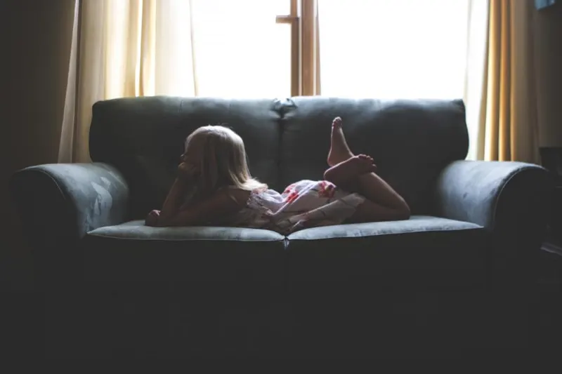 A child lying on a sofa, resting