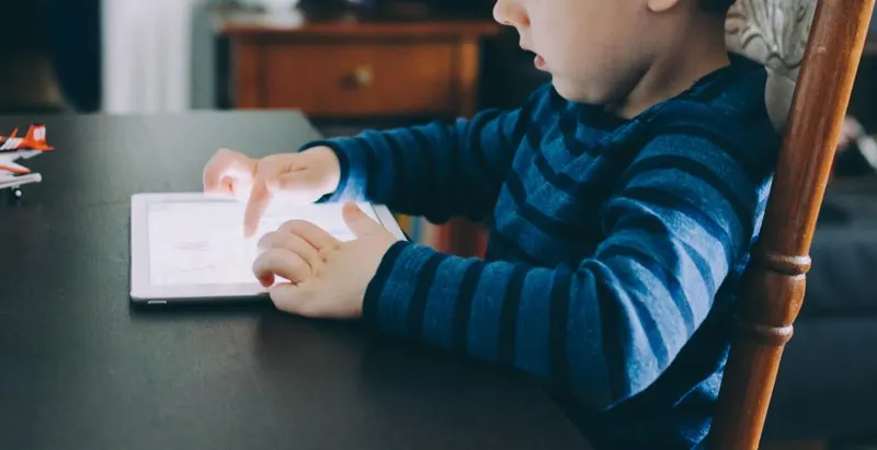 A child using a tablet at a table